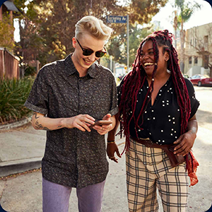 Two people laughing while walking on the street