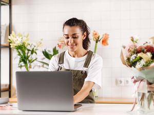 Woman smiling at laptop in a flower shop