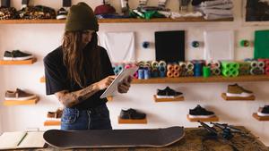 Frau in einem Skateboard-Shop, die ihr Business-Tablet checkt