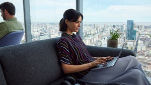 Woman sitting on a couch using a laptop.