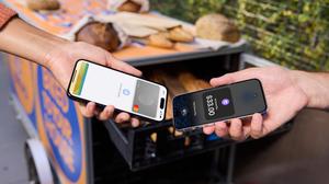 A business owner accepting payment through the Tap to Pay feature on iPhone through PayPal Zettle app from a customer using an Apple Watch.