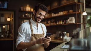 Manager smiling at his phone in front of cash register