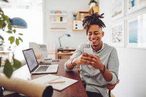 A guy at his home office using guest checkout option while shopping online on his mobile phone.