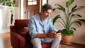man sitting on couch using mobile