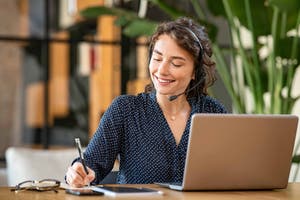 Customer service representative with a headset working at a laptop in an office.