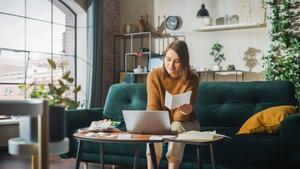 Businesswoman in a home environment on a laptop logging business receipts.