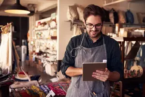 Hombre dueño de pequeña empresa trabajando en su tablet.