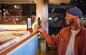 A man makes a contactless payment on his phone on a night out