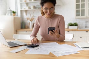 A woman smiles while looking at her phone