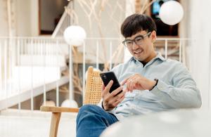 Man smiles while looking at a smartphone