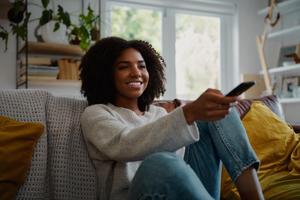 A woman points a remote control at a TV