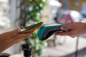 A person taps their phone to a payment terminal to make a contactless mobile payment.