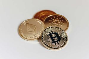 A physical coin with the Bitcoin logo and one with the Ethereum logo lay on top of two other coins.