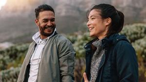 Man smiling at woman looking into the distance outside.