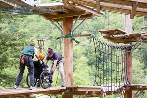 Person in wheelchair being helped out to an obstacle course at Dynamo Camp