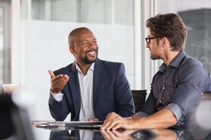 Two colleagues sitting at a computer in a business meeting