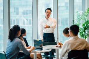 Business man speaking in front of a group of people in an executive office