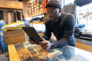 Un entrepreneur utilise une tablette dotée d'un système de caisse dans un magasin de vêtements