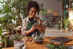 Female gardener sitting inside looking at phone