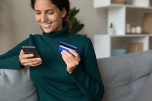 Woman at home holding her credit card and phone