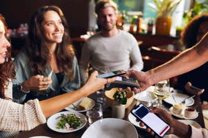 Group of friends making a contactless payment at a restaurant