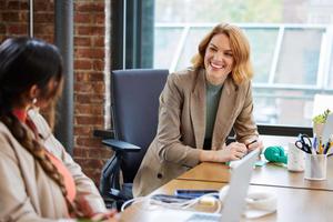 Two women in large enterprise office sitting at table laughing