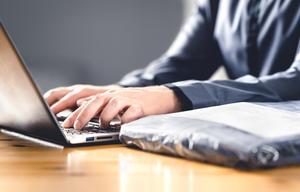 A man types on his laptop to setup a refund.