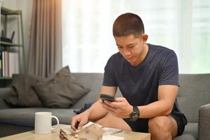 A man sits checks his phone to see if money went to a closed account.