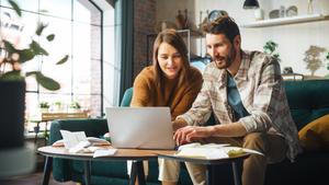 A couple looks at their laptop and documents to set short term financial goals.