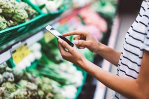 A woman checks her phone for cash back offers at the grocery store.