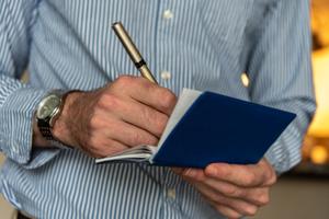 A man writes on a check in his checkbook.