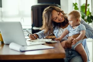 Woman holding baby on her lap reviewing finances