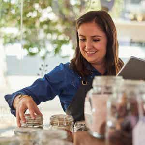 Smiling business owner checking her tea inventory in large glass mason jars