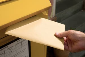 Brief wird in Briefkasten gesteckt