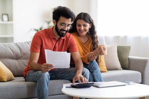 Glückliche Ehepartner prüfen Finanzdokumente und berechnen das Familienbudget zu Hause