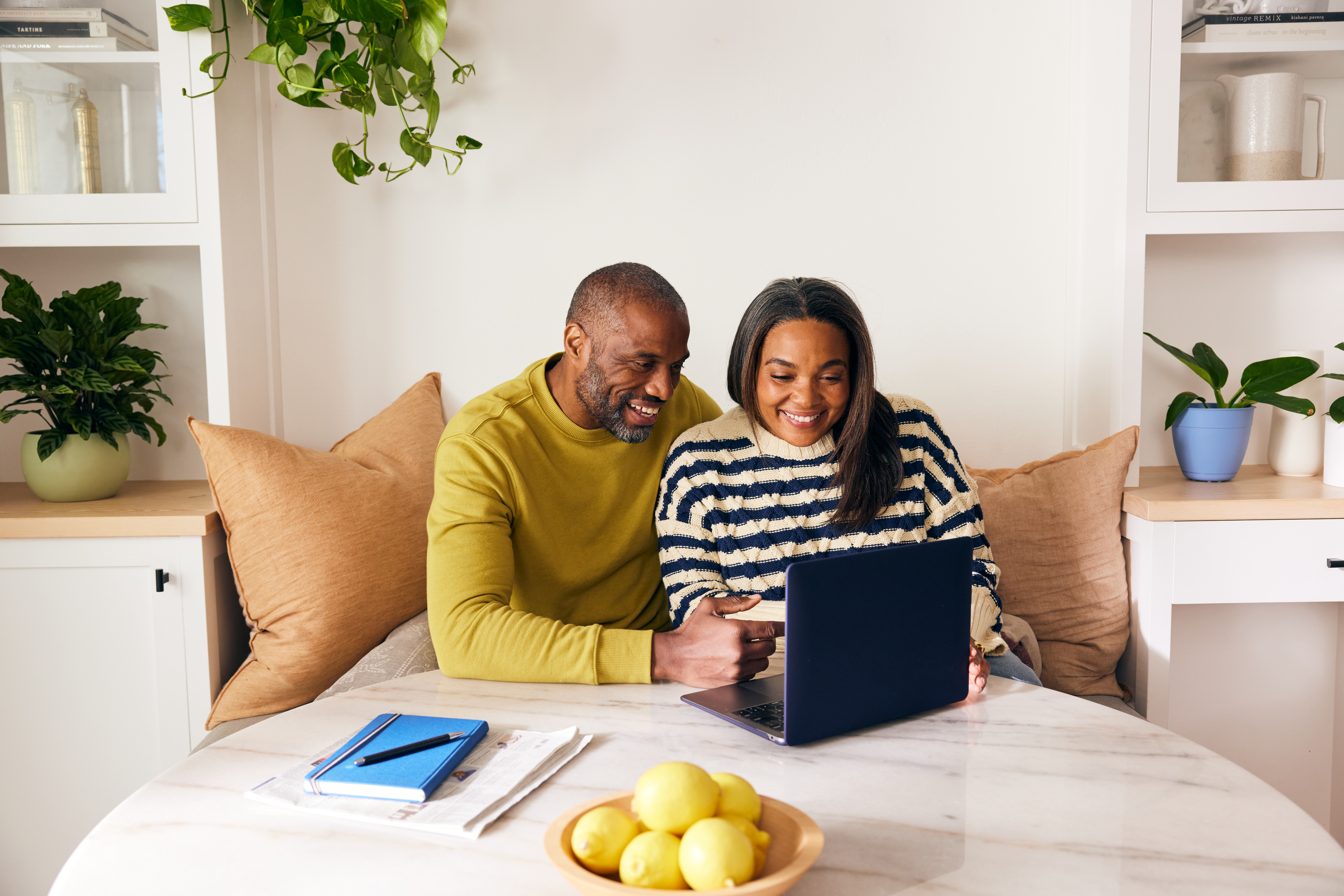 A man and woman sit together on a couch, focused on a laptop in front of them, sharing a moment of collaboration.