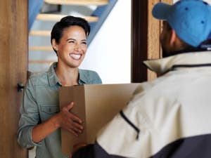 Woman receiving a package at her door from a courier service