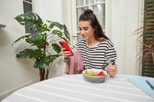 A woman holding a phone with a red phone case, highlighting its eye-catching color and contemporary design.