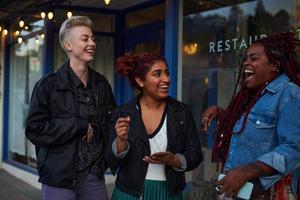 A cheerful scene of three women laughing outside a restaurant.