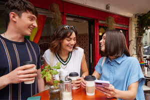 Three young friends chatting over coffee at a table in a cozy cafe