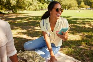 A woman relaxing on the grass, focused on her mobile phone.