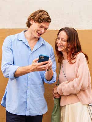 A man and a woman laughing at a phone