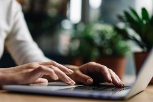 Close up of a man typing on his laptop.