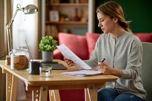 A woman looks at her bank statement to find her account number.