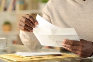 A man pulls a check out of an envelope.