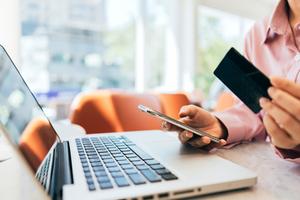 A woman holds her credit card and phone and updates her billing address.