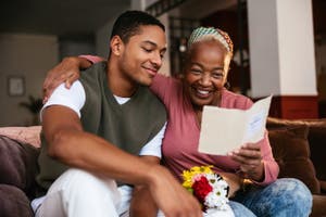 A man and his mother happily look at a birthday card.