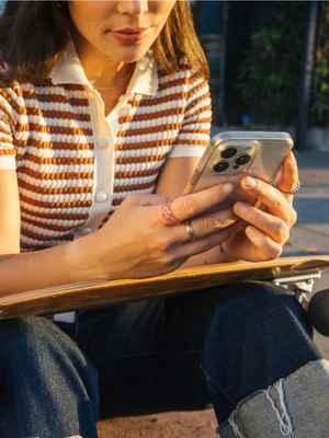 Woman looking at phone resting arms on a skateboard