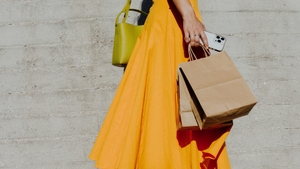 Woman in orange dress holding shopping bags and her phone