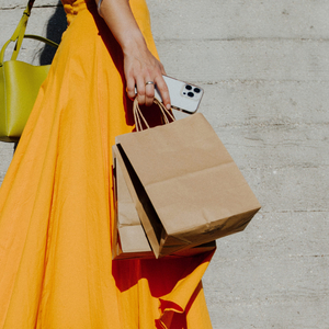 Woman in orange dress holding shopping bags and her phone